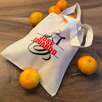 Monogramm 'J' Plotterdatei von easy-sticks auf einer Stofftasche, beschriftet mit 'JOSE EDUARDO', umgeben von frischen Orangen. Perfekt für personalisierte Geschenke.