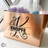 Monogramm 'K' Plotterdatei von easy-sticks auf einer glänzenden roségoldenen Box mit lila Knöpfen. Perfekt für kreative DIY-Projekte.