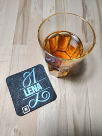 Filzuntersetzer mit dem stilvollen Monogramm "L" aus der Plotterdatei von easy-sticks, personalisiert mit dem Namen "LENA" und einem Glas Getränk im Hintergrund für kreative DIY-Ideen.