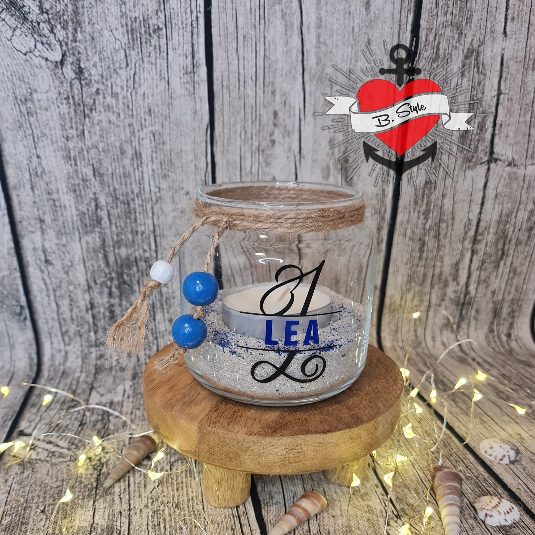 Schlichtes Glas mit einer Kerze und dem Monogramm "L" aus der Plotterdatei von easy-sticks, personalisiert mit dem Namen "LEA", auf einem rustikalen Holzring, ideal für persönliche Geschenke.