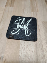 Monogramm "M" Plotterdatei auf einem schwarzen Filzuntersetzer mit dem Namen "MAIK", designt von easy-sticks. Perfekte Wahl für DIY-Projekte.