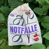 Monogramm 'N' Plotterdatei von easy-sticks, auf einer Stofftasche für Notfälle gedruckt, umgeben von grünen Blättern.