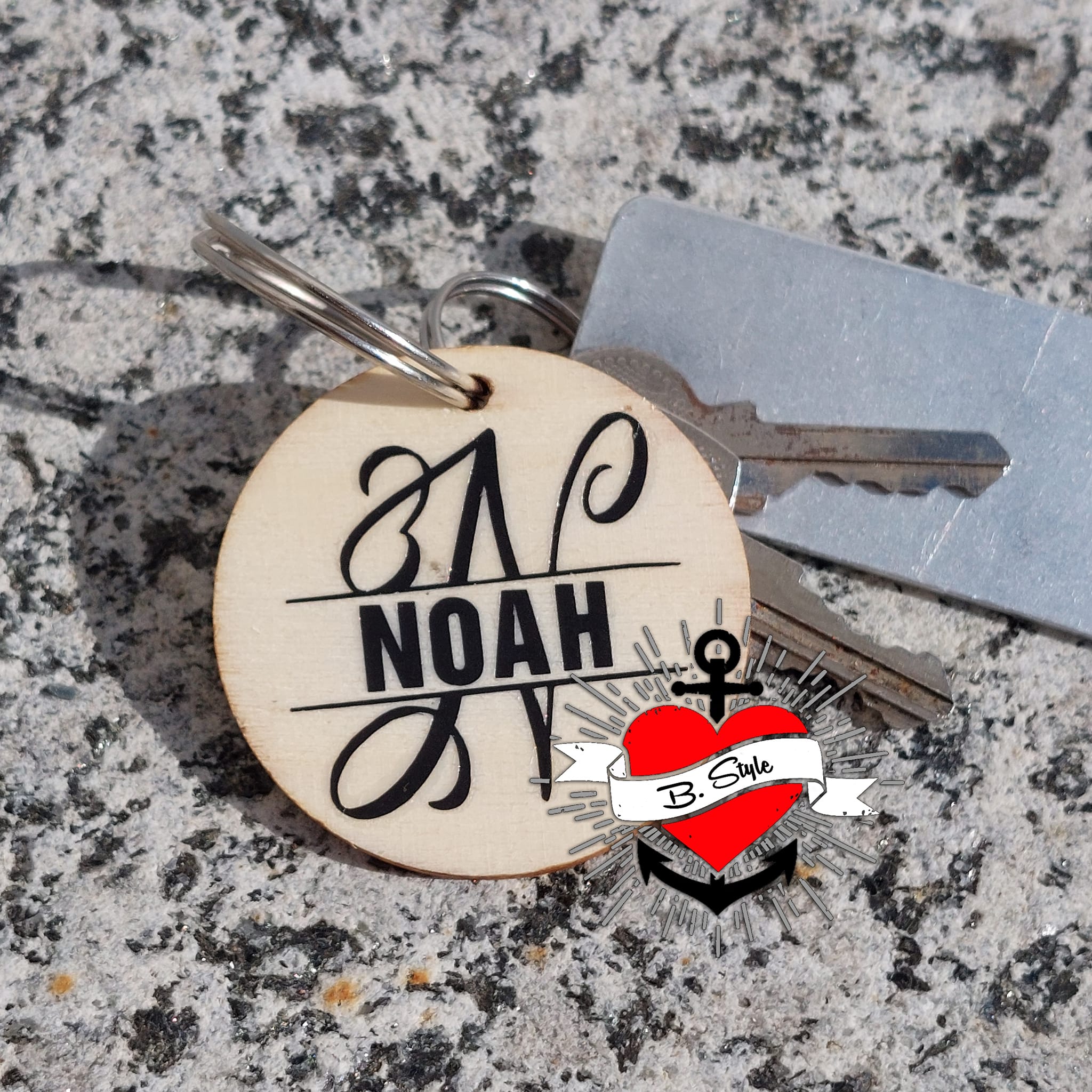 Monogramm 'N' Plotterdatei von easy-sticks, graviert auf einem Schlüsselanhänger aus Holz, neben Schlüsseln auf einer Felsoberfläche.