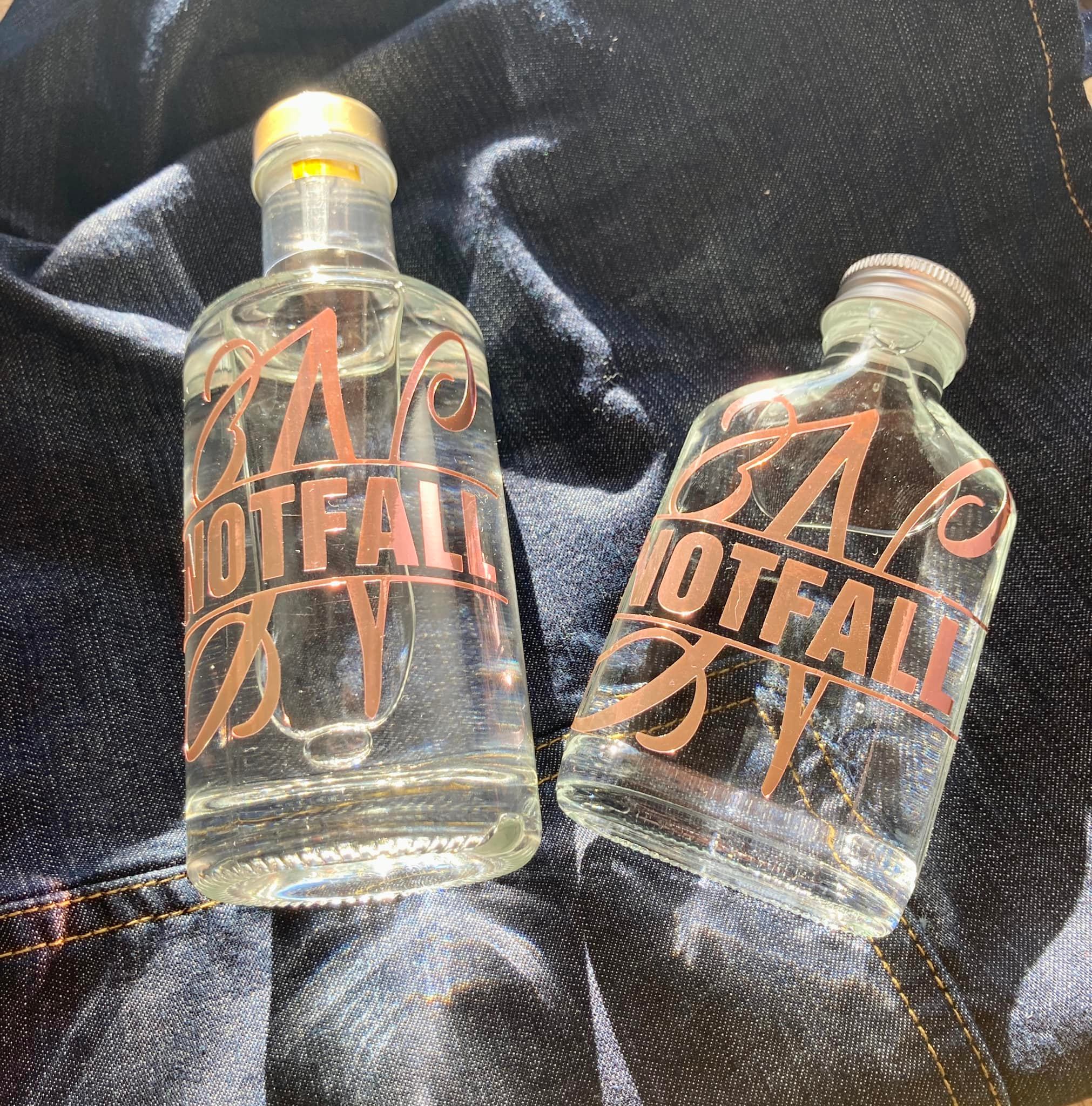 Zwei klare Glasflaschen mit dem Monogramm "NOTFALL" von easy-sticks, ideal für die stilvolle Aufbewahrung von Flüssigkeiten.