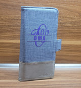 Elegante Brieftasche mit Monogramm "O" Plotterdatei von easy-sticks, personalisiert mit dem Wort "OMA" in lila auf einem grauen Textil-Material.