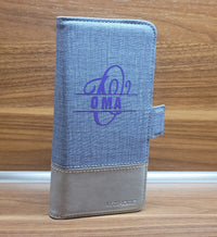Elegante Brieftasche mit Monogramm "O" Plotterdatei von easy-sticks, personalisiert mit dem Wort "OMA" in lila auf einem grauen Textil-Material.