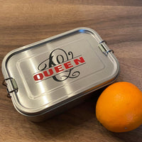 Blechdose mit Monogramm 'Q' Plotterdatei von easy-sticks, dekoriert mit dem Schriftzug 'QUEEN' und frisch gepflückter Orange.