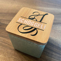 Stylische Glasbox mit Bambusdeckel, beschriftet mit 'SCHÖGGELI', ein kreatives Bastelprojekt unter Verwendung der Monogram 'S' Plotterdatei von easy-sticks.