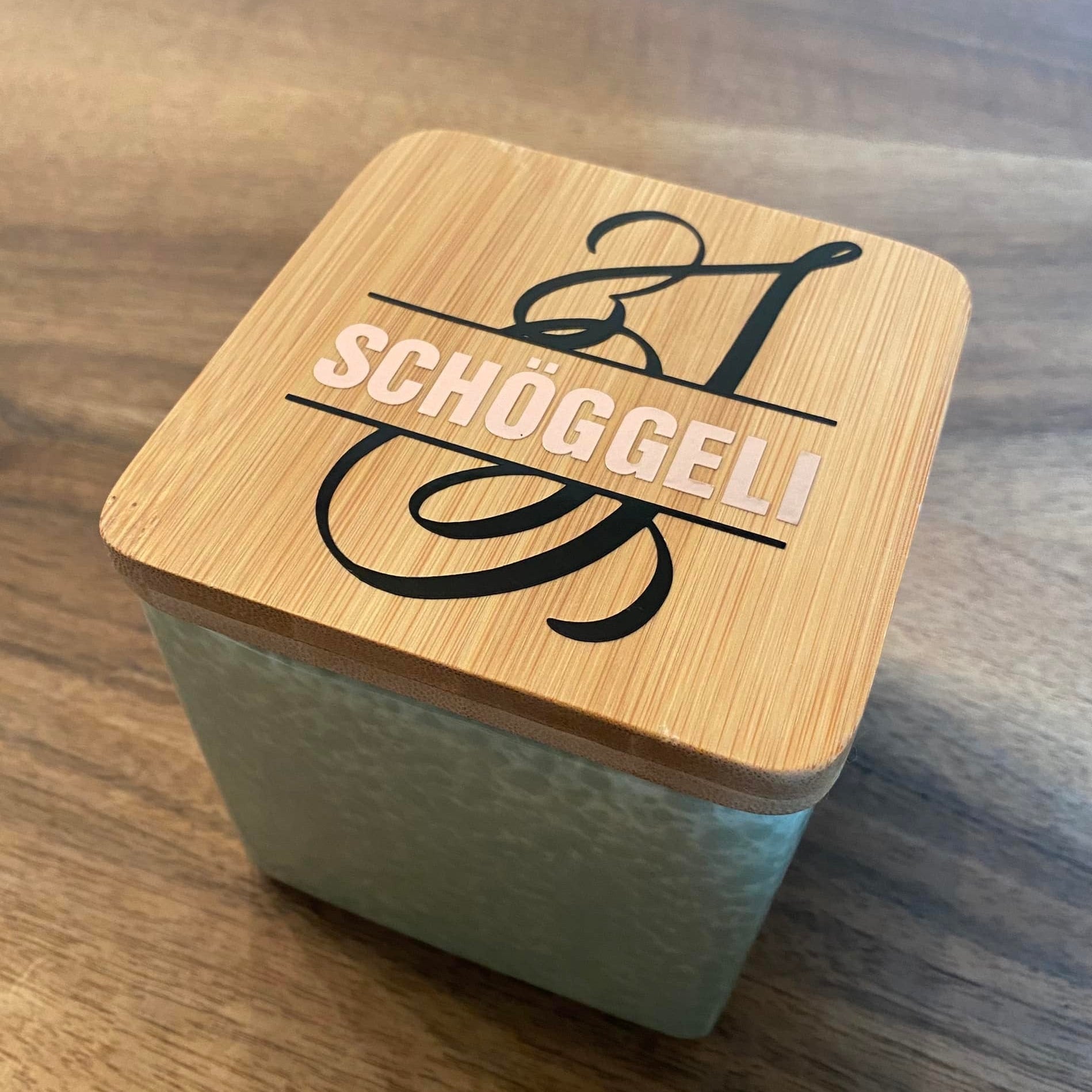 Stylische Glasbox mit Bambusdeckel, beschriftet mit 'SCHÖGGELI', ein kreatives Bastelprojekt unter Verwendung der Monogram 'S' Plotterdatei von easy-sticks.