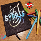 Glitzerndes Notizbuch mit Monogramm 'S' von easy-sticks, umgeben von bunten Stiften, ideal für kreative Notizen und Skizzen.