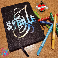 Glitzerndes Notizbuch mit Monogramm 'S' von easy-sticks, umgeben von bunten Stiften, ideal für kreative Notizen und Skizzen.