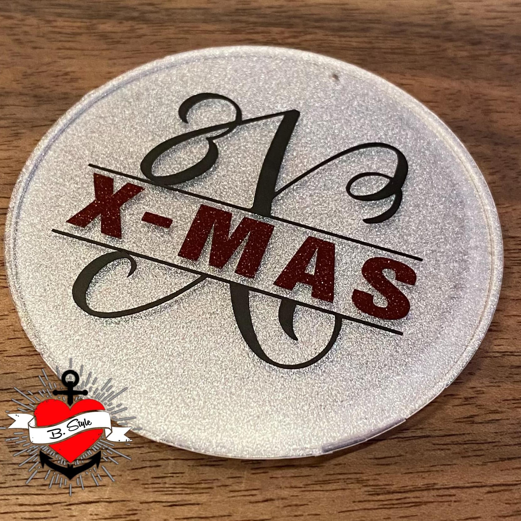 Festliche Nutzung der Monogramm "X" Plotterdatei von easy-sticks, abgebildet auf einem glänzenden runden Objekt mit dem Schriftzug "X-MAS", perfekt für saisonale Dekoration.
