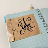 Virtuelle Anwendung der Monogramm "X" Plotterdatei von easy-sticks, gezeigt auf einem Notizbuch mit einem gestylten XOXO Design, ideal für persönliche Bastelprojekte.