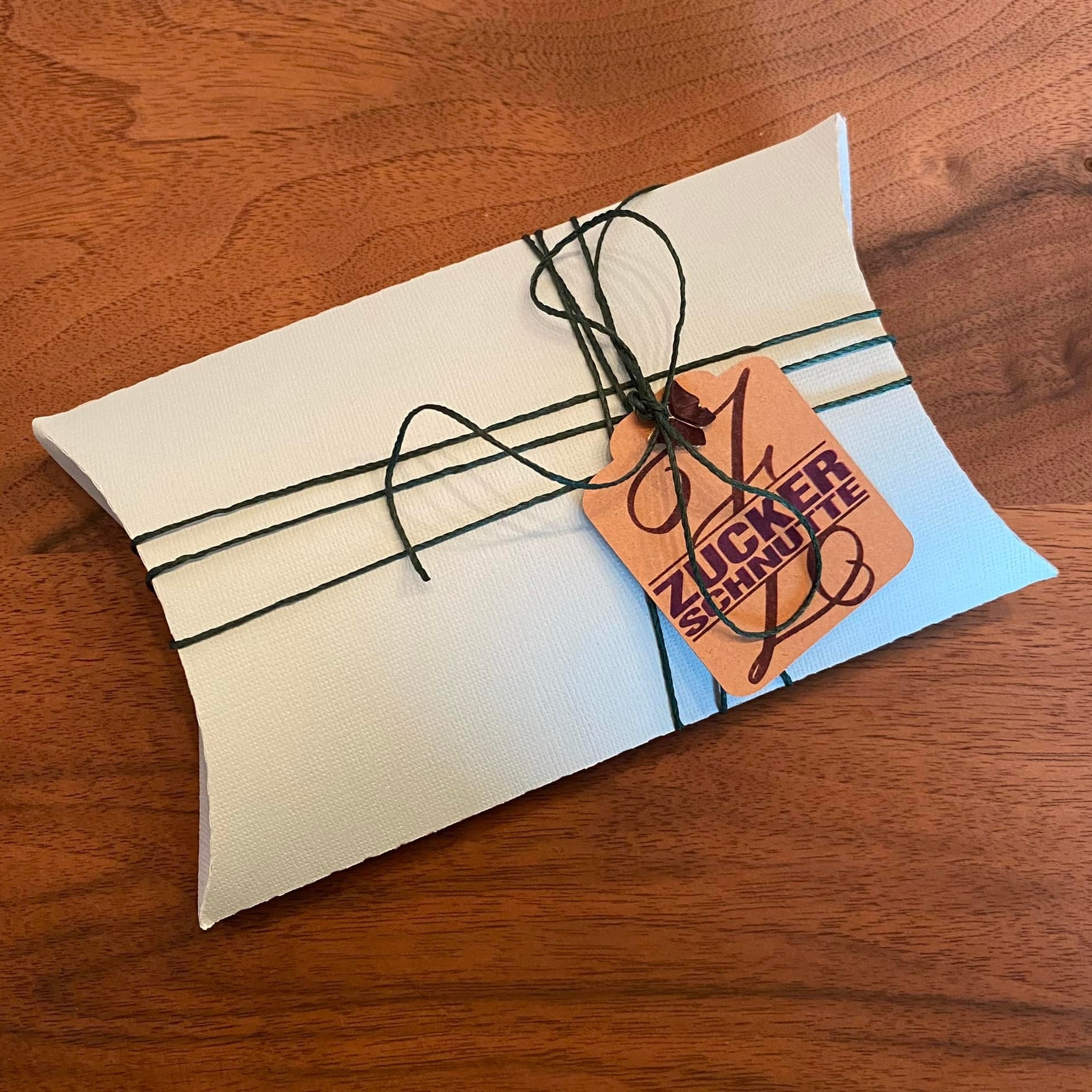 Kreative Geschenkverpackung mit einem Tag, der das Monogramm "Z" und den Schriftzug "ZUCKERSCHNÜTTE" von easy-sticks zeigt, ideal für individuelle Geschenke.