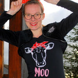 Junge Frau mit einer roten Schleife im Haar, die ein schwarzes T-Shirt mit einem Kuh-Design und dem Schriftzug 'MOO' trägt, entworfen von easy-sticks.
