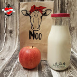 Originelle Moo Plotterdatei von easy-sticks, präsentiert eine Kuh auf einer Papiertüte, zusammen mit einer Flasche Milch und einem Apfel.