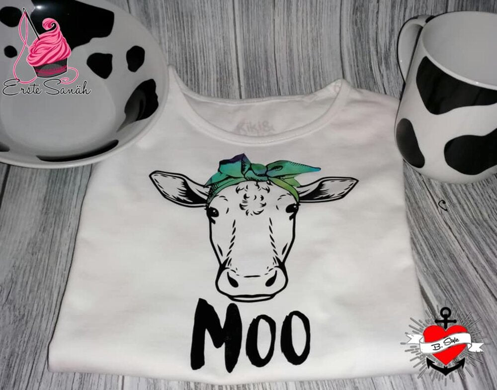 Weißes T-Shirt mit einem charmanten Kuh-Motiv und dem Schriftzug 'MOO', präsentiert zusammen mit passenden Tassen und Schalen von easy-sticks.