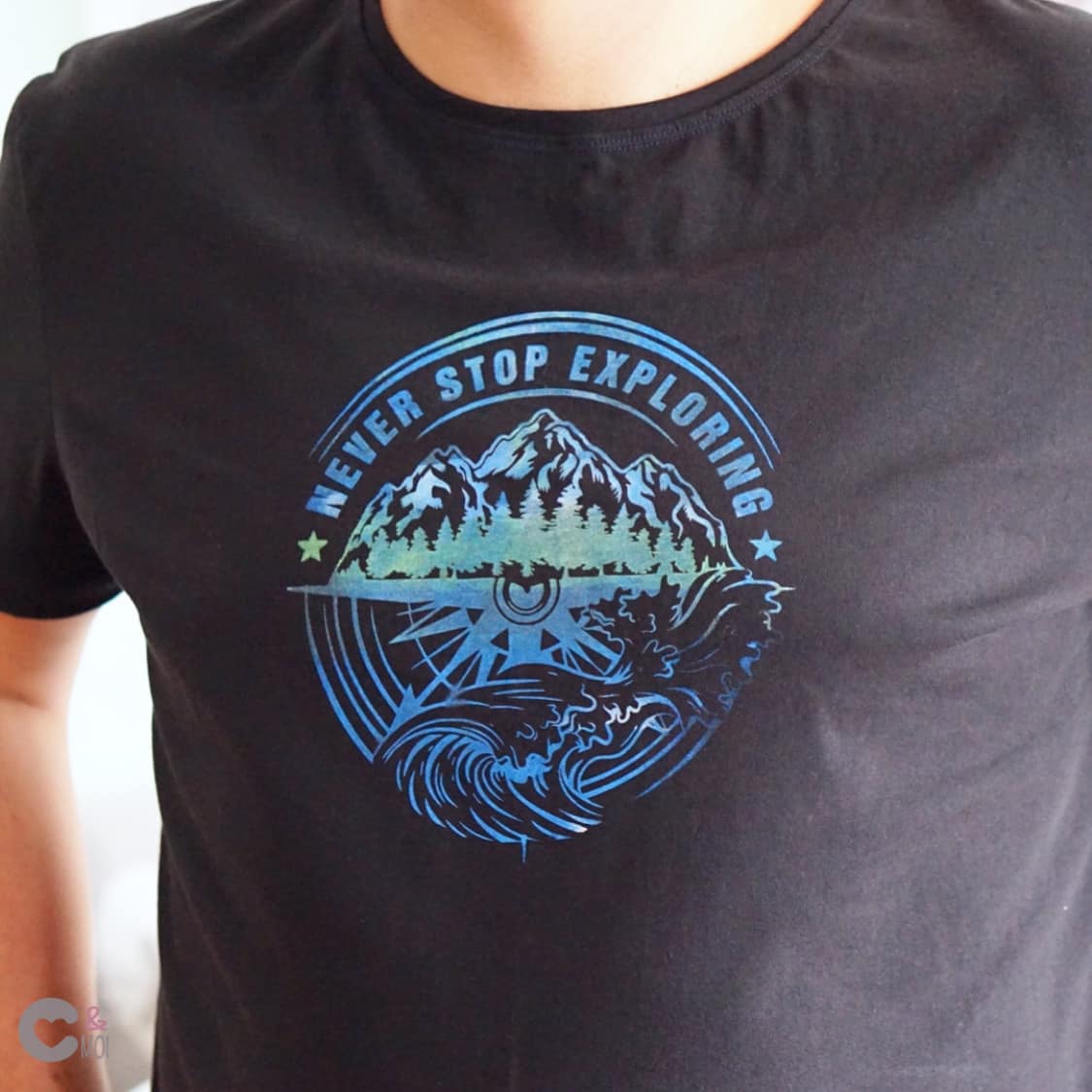 Schwarzes T-Shirt mit dem Aufdruck "NEVER STOP EXPLORING" in Blau- und Grüntönen, ideal für kreative Arbeiten mit der Plotterdatei von easy-sticks.