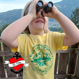 Kind im gelben T-Shirt mit dem Aufdruck "NEVER STOP EXPLORING" und Fernglas, inspiriert von der Plotterdatei von easy-sticks.