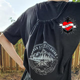 Eine Person trägt einen schwarzes Rucksack mit dem Design "NEVER STOP EXPLORING", das Teil der Plotterdatei von easy-sticks ist. Der Rucksack zeigt eine Berglandschaft und das inspirierende Motto, perfekt für kreative Projekte.