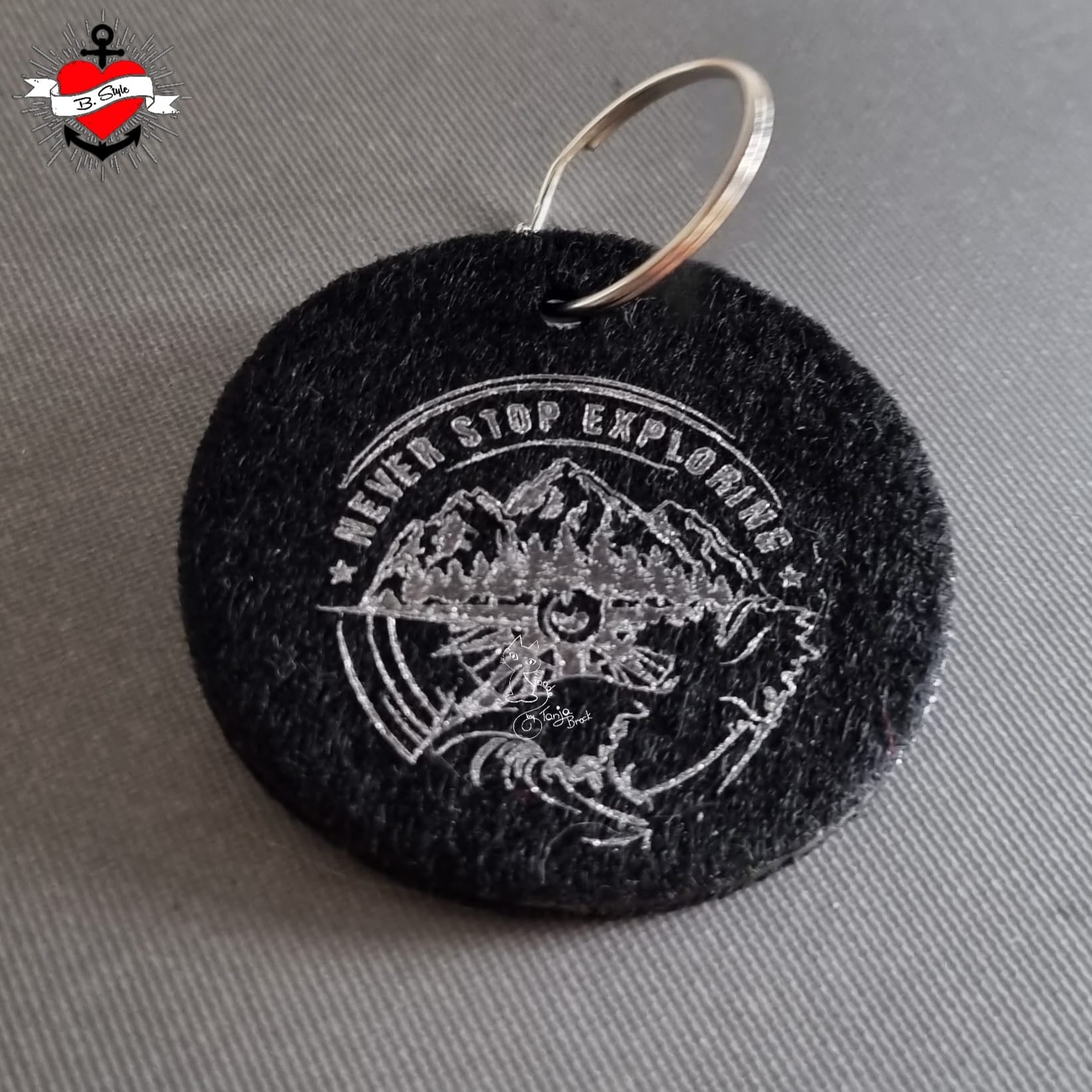 Nahaufnahme eines Anhängers aus Filz mit dem Motiv "NEVER STOP EXPLORING" von easy-sticks, erstellt aus der einzigartigen Plotterdatei, perfekt für kreative DIY-Projekte.
