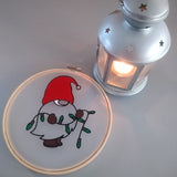 Nikolaus Wichtel Plotterdatei von easy-sticks, Wichtel in einem Stickrahmen neben einer Laterne, die eine gemütliche Atmosphäre vermittelt.