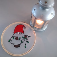 Nikolaus Wichtel Plotterdatei von easy-sticks, Wichtel in einem Stickrahmen neben einer Laterne, die eine gemütliche Atmosphäre vermittelt.