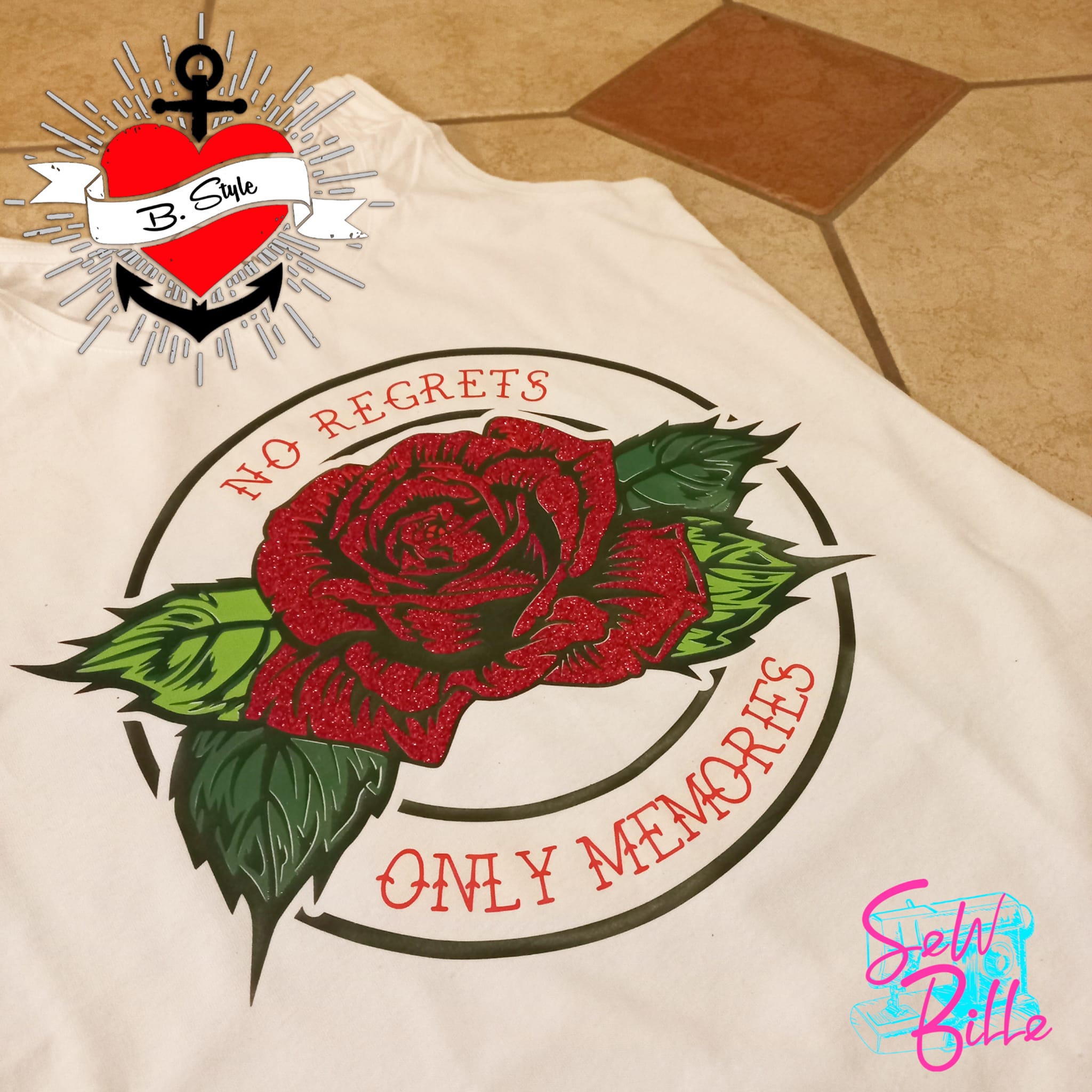 T-Shirt mit dem eleganten Aufdruck "No Regrets Only Memories" von easy-sticks, das eine glitzernde rote Rose zeigt, bereitgestellt auf einem gefliestem Untergrund.
