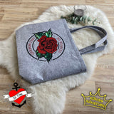 Stofftasche mit dem Aufdruck "No Regrets Only Memories" von easy-sticks, verziert mit einer roten Rose und grünen Blättern, vorsichtig drapiert auf einem weichen Hintergrund.