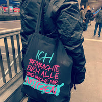 Dunkle Tragetasche mit dem markanten Spruch "ICH BEOBACHTE EUCH ALLE UND MACHE MIR NOTZEN" von easy-sticks, perfekt für den Alltag und kreative Projekte.