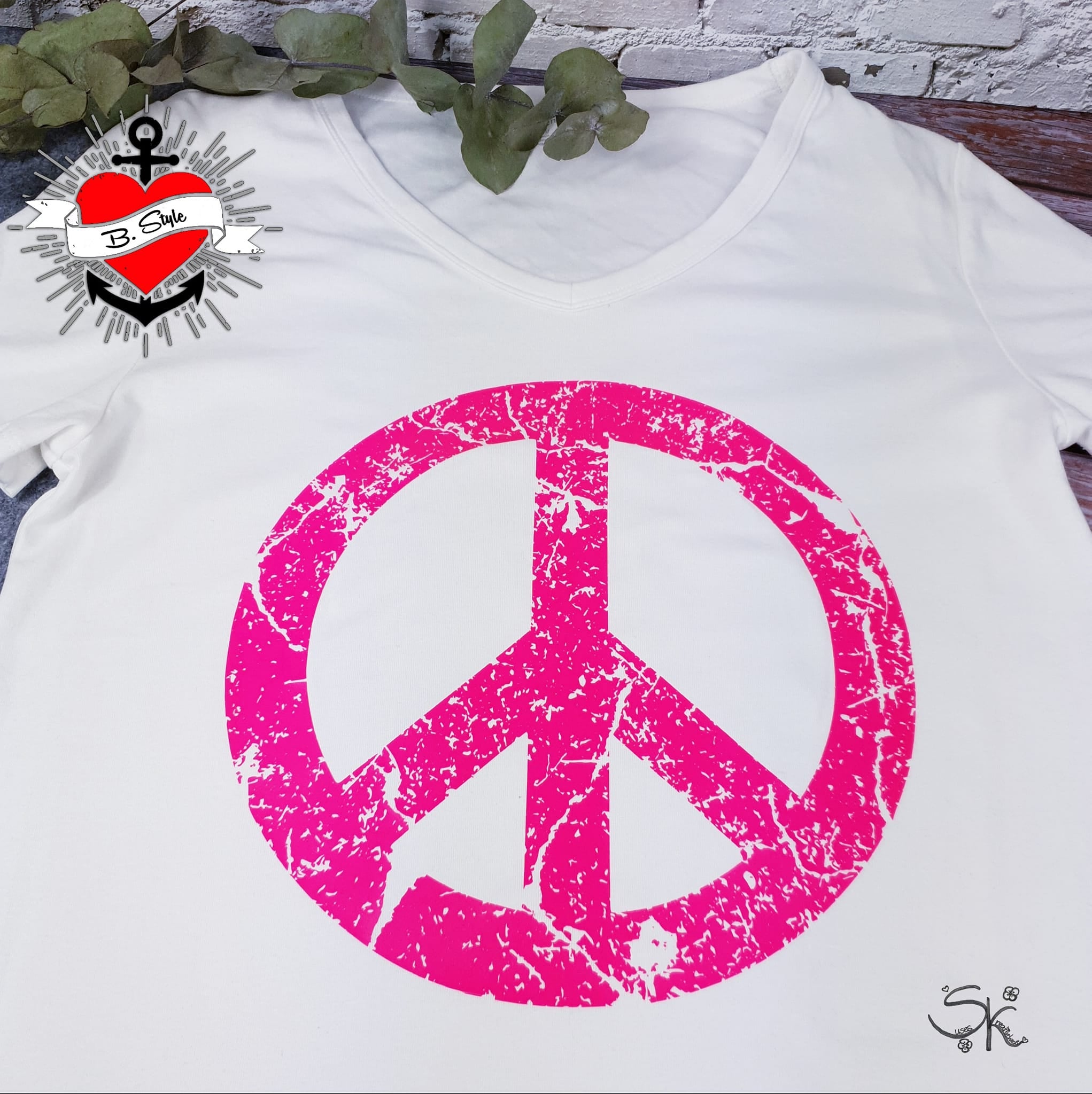 Ein weißes V-Ausschnitt-Shirt mit einem pinken Peace-Design, das auf der "PEACE" Grunge Schriftart Plotterdatei von easy-sticks basiert. Ideal für individuelle Designs! Plotterdatei.