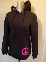 Eine schwarze Kapuzenshirt mit pinken Schriftzügen "PEACE" und "LOVE" sowie einem Peace-Symbol, designt aus der "PEACE" Grunge Schriftart Plotterdatei von easy-sticks. Perfekt für trendy Outfits! Plotterdatei.