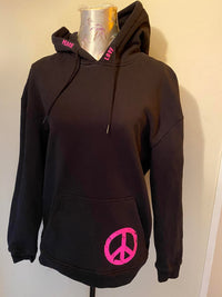 Eine schwarze Kapuzenshirt mit pinken Schriftzügen "PEACE" und "LOVE" sowie einem Peace-Symbol, designt aus der "PEACE" Grunge Schriftart Plotterdatei von easy-sticks. Perfekt für trendy Outfits! Plotterdatei.