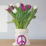 Eine Stofftasche mit einem lila Peace-Symbol, die Blumen präsentiert, entworfen mit der "PEACE" Grunge Schriftart Plotterdatei von easy-sticks. Ideal für kreative DIY-Gestaltungen! Plotterdatei.