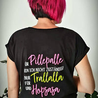 Rückansicht einer Person mit pinker Frisur in einem schwarzen Shirt, das den auffälligen Spruch "Für Pillepalle bin ich nicht zuständig! Nur für Trallalla und für Hopsasa" zeigt, inspiriert durch die Plotterdatei von easy-sticks.
