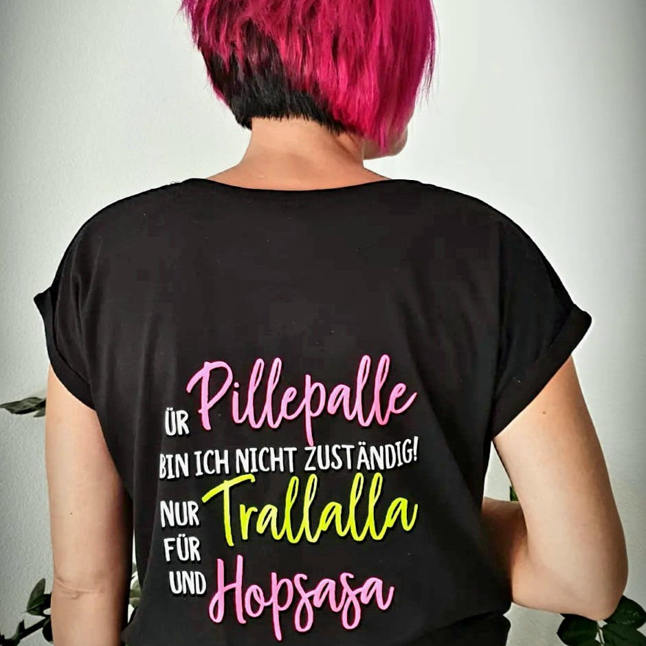 Rückansicht einer Person mit pinker Frisur in einem schwarzen Shirt, das den auffälligen Spruch "Für Pillepalle bin ich nicht zuständig! Nur für Trallalla und für Hopsasa" zeigt, inspiriert durch die Plotterdatei von easy-sticks.