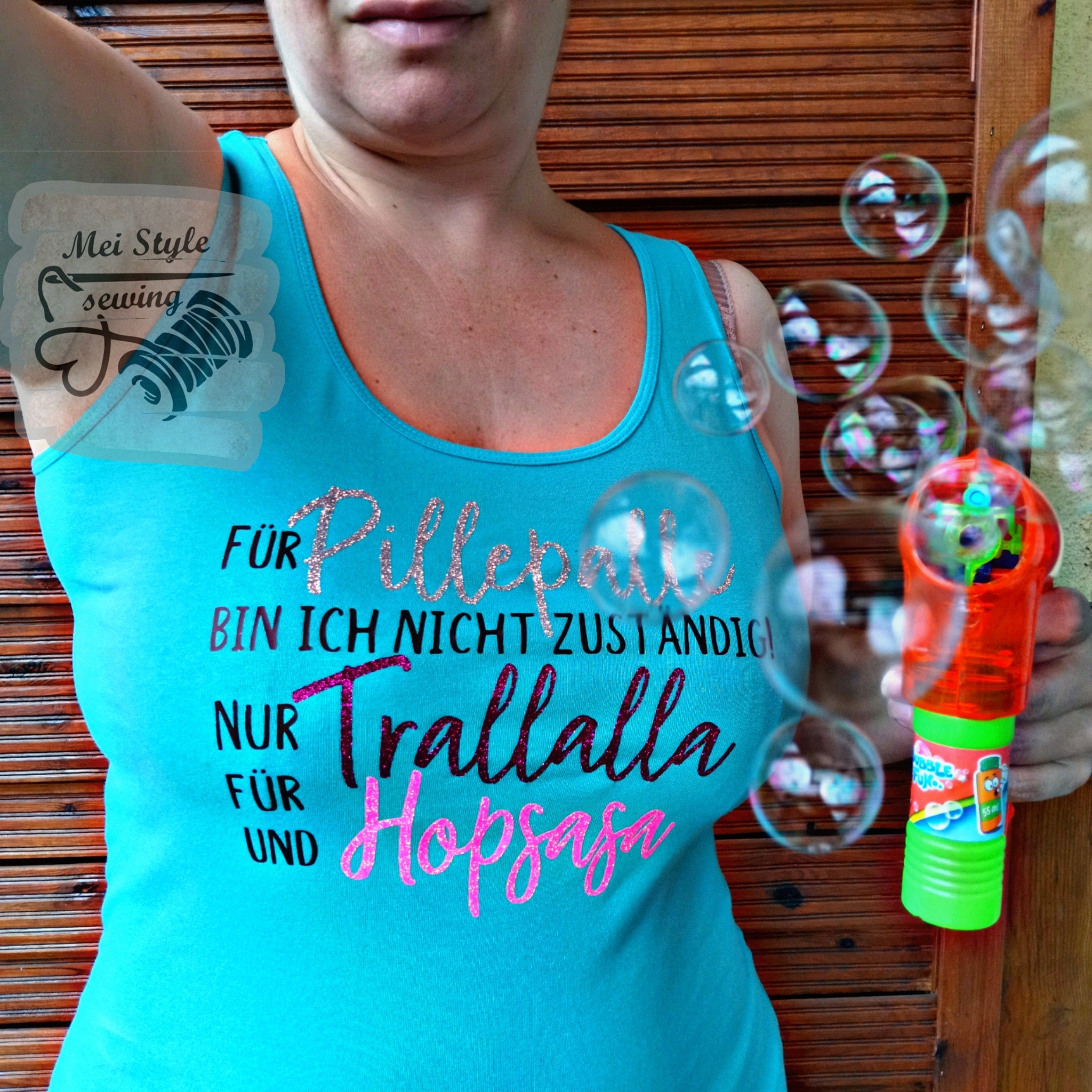 Frau hält eine Seifenblasenmaschine, während sie ein Top mit dem Aufdruck "Für Pillepalle bin ich nicht zuständig! Nur für Trallalla und für Hopsasa" von easy-sticks trägt, eine kreative Umsetzung der Plotterdatei.