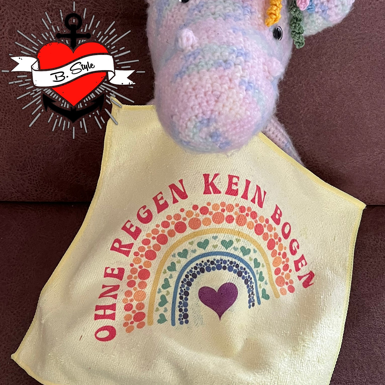 Ein gehäkeltes Unicorn mit einem Tuch, das das Design 'Ohne Regen kein Bogen' zeigt, kreiert von easy-sticks und basierend auf der Plotterdatei 'Regenbogen - Ohne Regen kein Bogen'.