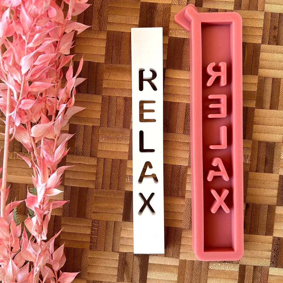 Easy-Sticks Silikonform "Relax" mit einzigartigen Gießformen, die für kreative Windlichter und Lichthäuser verwendet werden können. Die Abbildung zeigt die Silikonform in Pink neben einer abgedruckten Form des Schriftzugs "RELAX" in Weiß, perfekt für individuelle Dekorationen.