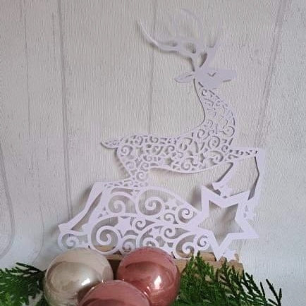 Kreative Rentier Plotter Datei von easy-sticks, filigranes, weißes Rentierdesign auf einer Holzplatte mit Weihnachtskugeln, ideal für DIY-Projekte.
