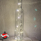 Eine dekorative Glasflasche mit Lichtern und dem Schriftzug "RESPEKT", gestaltet mit der "Respekt" Plotterdatei von easy-sticks. Eine einzigartige Ambiance für jedes Zuhause.