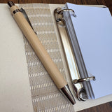 Bamboo-Stift auf einem weißen Ringbuch mit blanko Seiten, ideal für kreative Projekte mit der Laserdatei von Easy-Sticks.