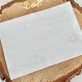 Frohe Weihnachten Rub on UV Sticker Mix5 in weiß von easy-sticks auf einem Holzuntergrund, präsentiert die stilvollen, randlosen Sticker mit festlichen Schriftzügen.