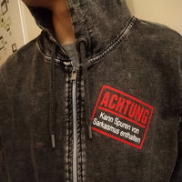 Nahaufnahme eines Hoodies mit der Aufschrift "Achtung - Kann Spuren von Sarkasmus enthalten" von easy-sticks, ideal für lässige Outfits mit Charakter.