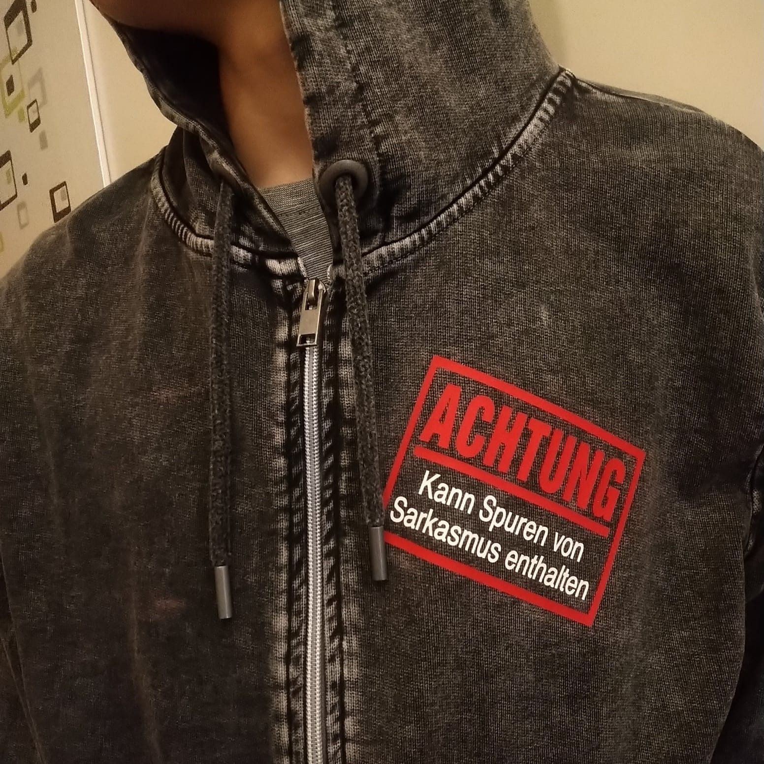 Nahaufnahme eines Hoodies mit der Aufschrift "Achtung - Kann Spuren von Sarkasmus enthalten" von easy-sticks, ideal für lässige Outfits mit Charakter.