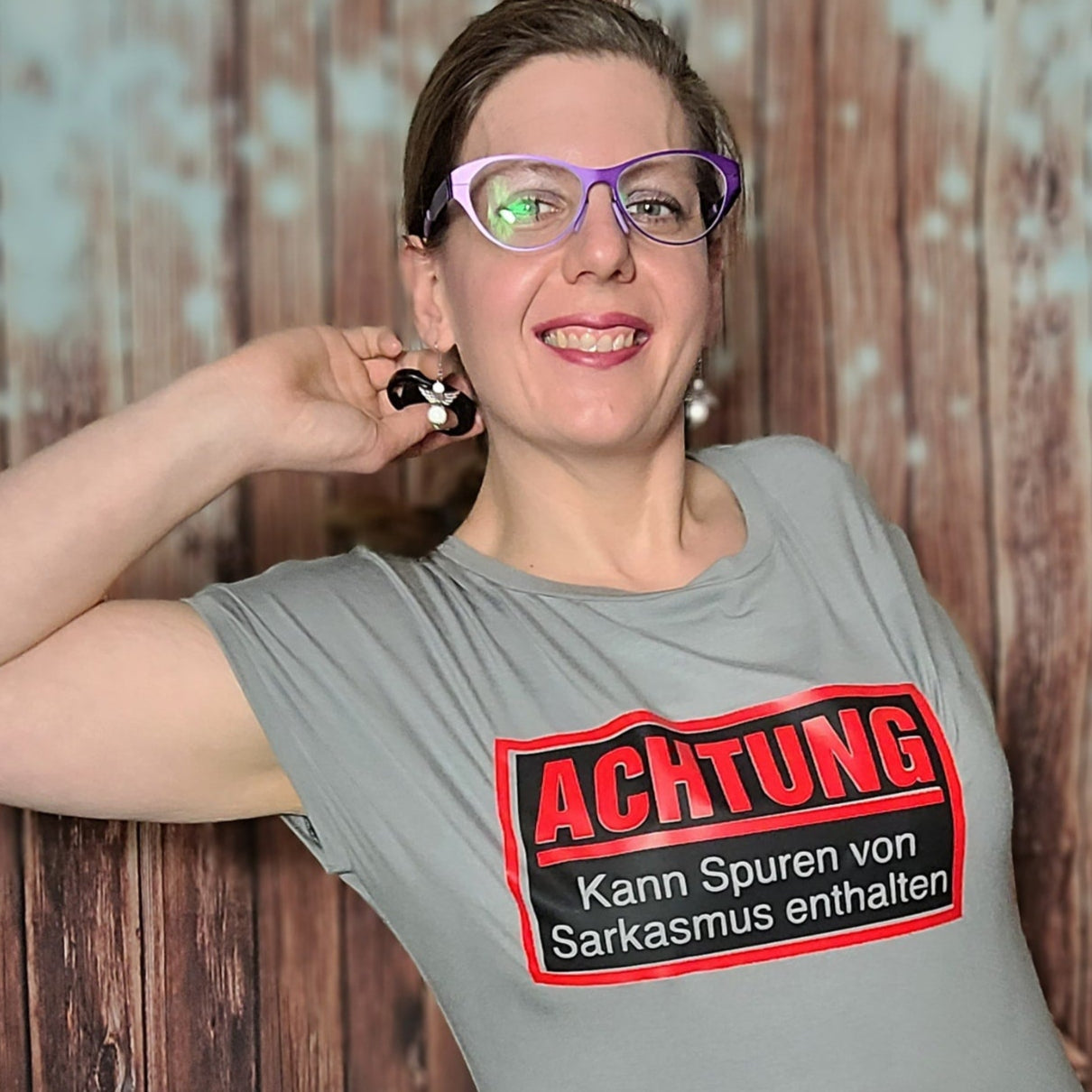 Portrait einer Person in einem grauen T-Shirt mit dem Aufdruck 'Achtung - Kann Spuren von Sarkasmus enthalten' von easy-sticks, ideal für kreative Projekte.