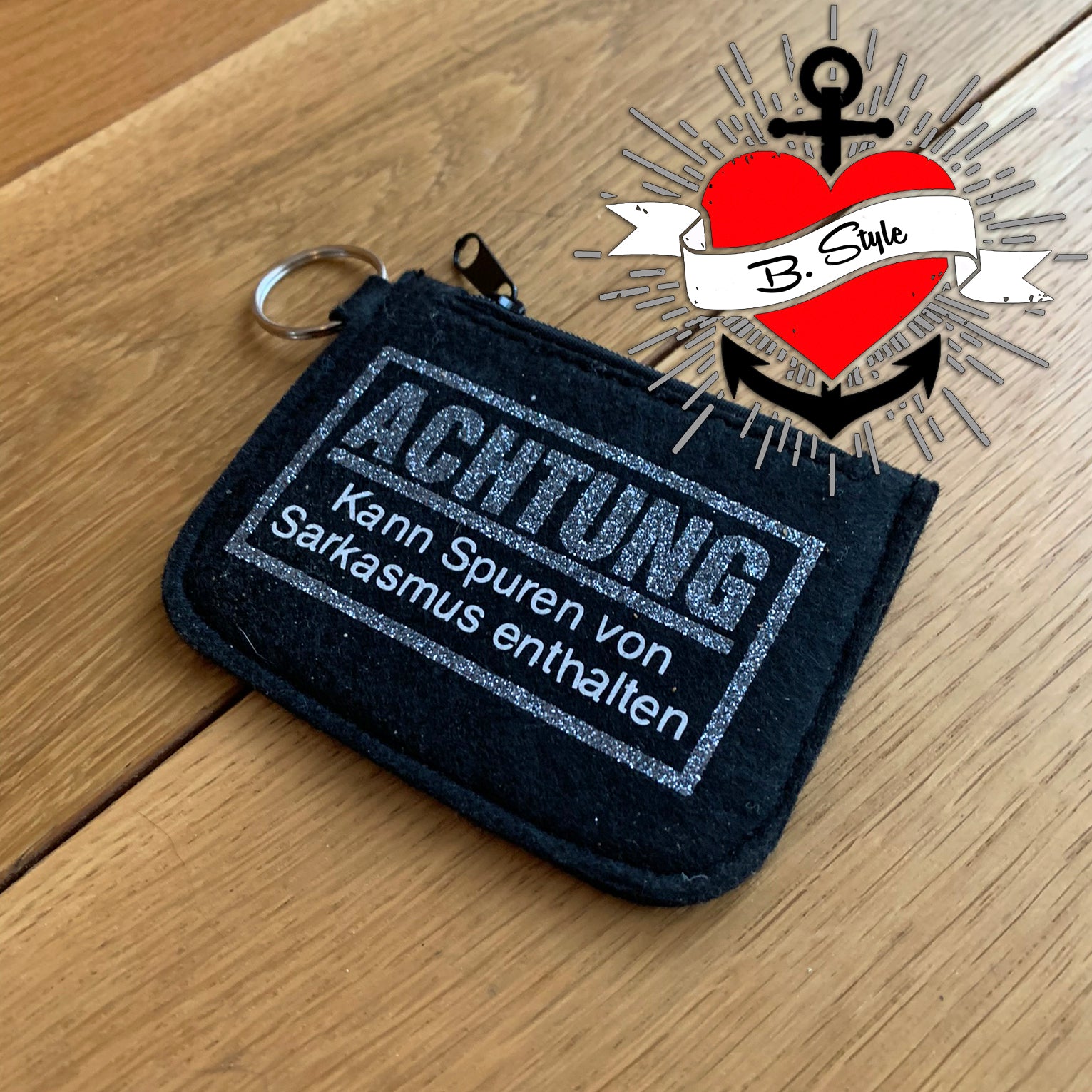 Schwarze Geldbörse mit Glitzer und der Aufschrift "Achtung - Kann Spuren von Sarkasmus enthalten" von easy-sticks, perfekt für kreative Menschen.