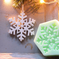 Weißer Schneeflockenanhänger und grüne Silikonform zum Aufhängen von easy-sticks, perfekt für kreative Winterdekorationen.