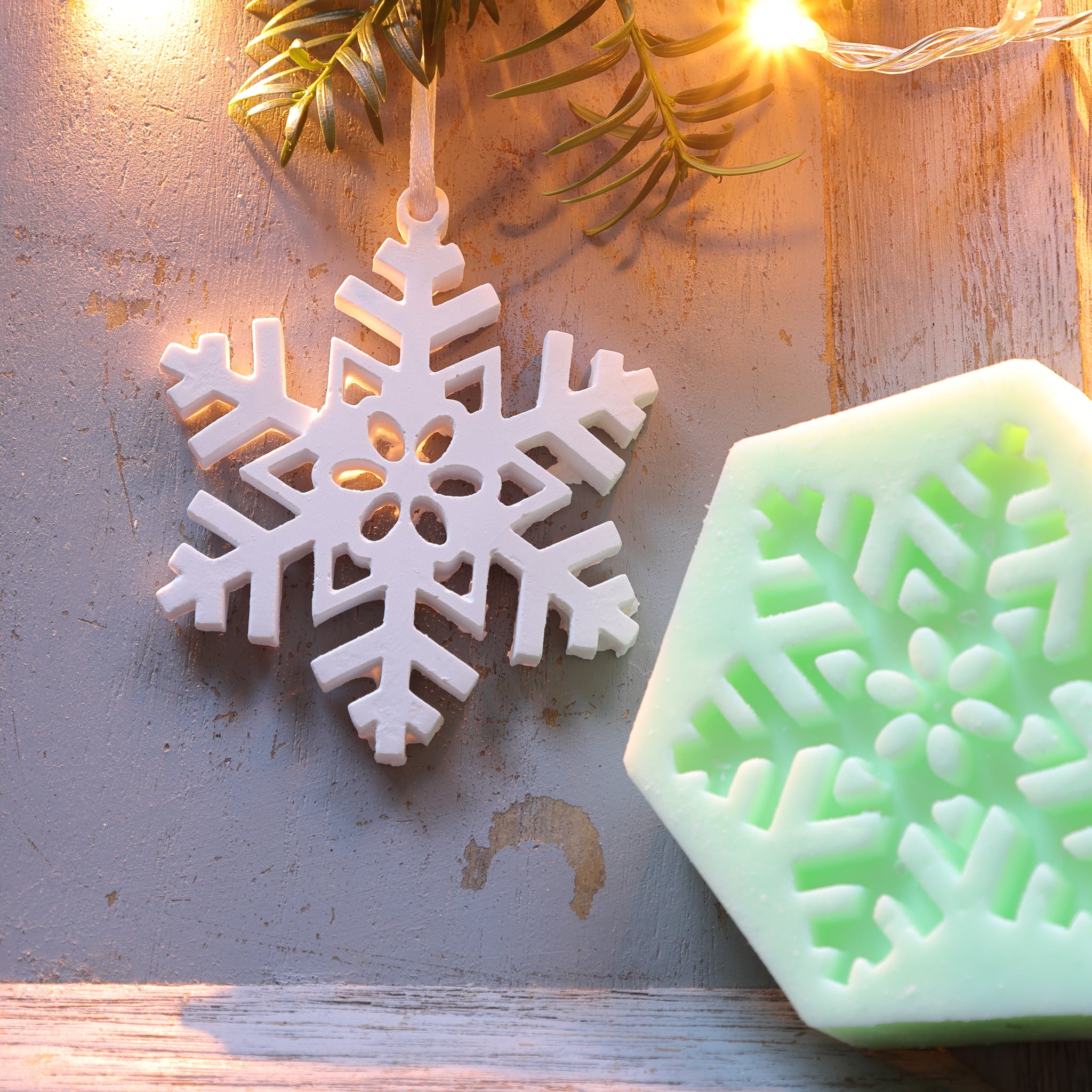 Weißer Schneeflockenanhänger und grüne Silikonform zum Aufhängen von easy-sticks, perfekt für kreative Winterdekorationen.