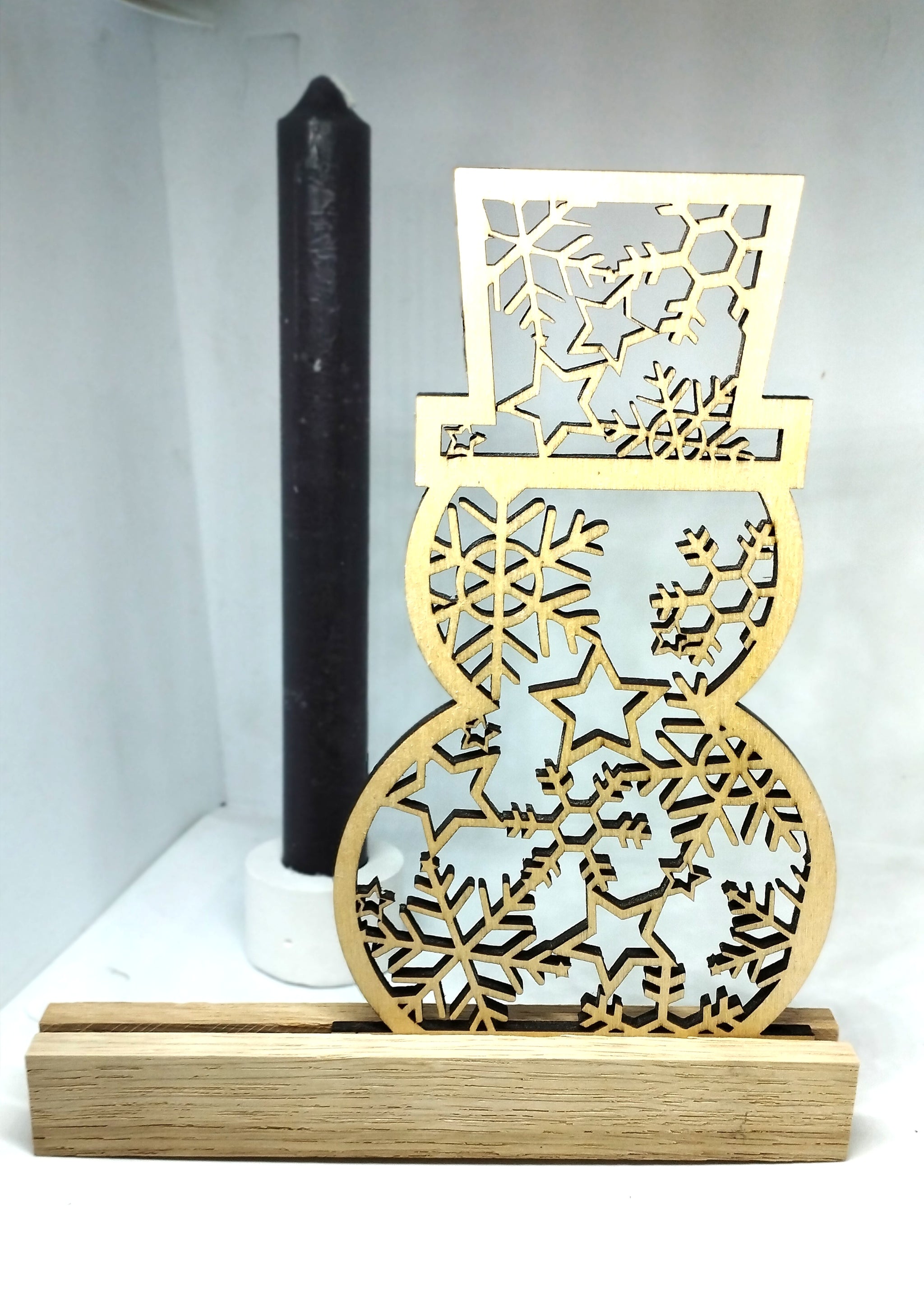 Schneemann Plotterdatei von easy-sticks, eleganter Holzschneemann auf Holzständer, akzentuiert von einer dekorativen Kerze. Ein kreatives Element für winterliche Dekoration.